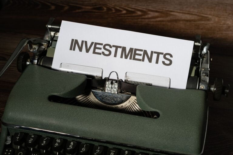 A green vintage typewriter with a sheet of paper reading "Investments"