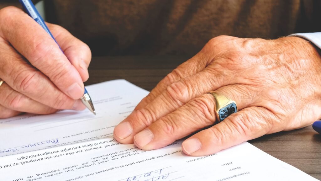 Person signing a document with a pen