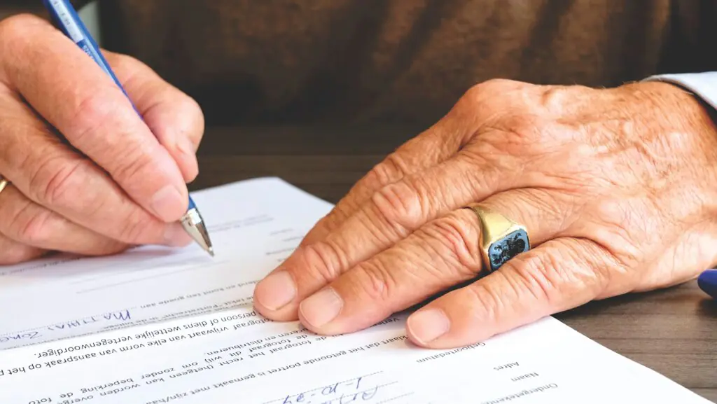 Person signing a document with a pen