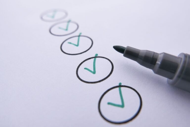 A marker pen beside a row of circles with green check marks on white paper